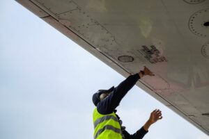 man wearing yellow vest standing under airplane
